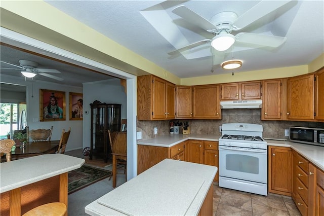 421 N Nettleton Ave, Bonner Springs, KS 66012 - kitchen with gas range gas stove, under cabinet range hood, stainless steel microwave, a ceiling fan, and brown cabinets