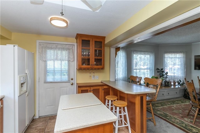 421 N Nettleton Ave, Bonner Springs, KS 66012 - kitchen featuring white refrigerator with ice dispenser, brown cabinets, a peninsula, light countertops, and plenty of natural light