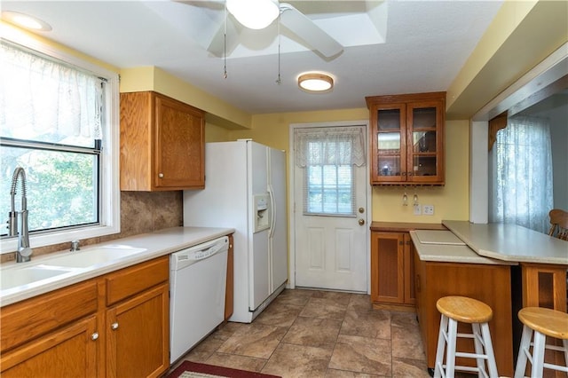 421 N Nettleton Ave, Bonner Springs, KS 66012 - kitchen featuring white appliances, brown cabinetry, glass insert cabinets, and a peninsula