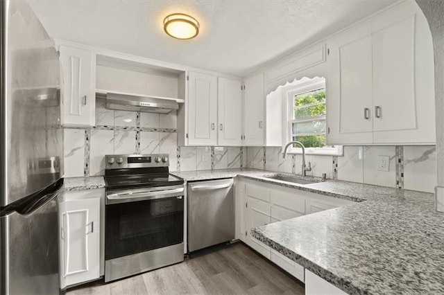 13623 W 95th St, Lenexa, KS 66215 - kitchen featuring appliances with stainless steel finishes, ventilation hood, white cabinetry, decorative backsplash, and wood finished floors