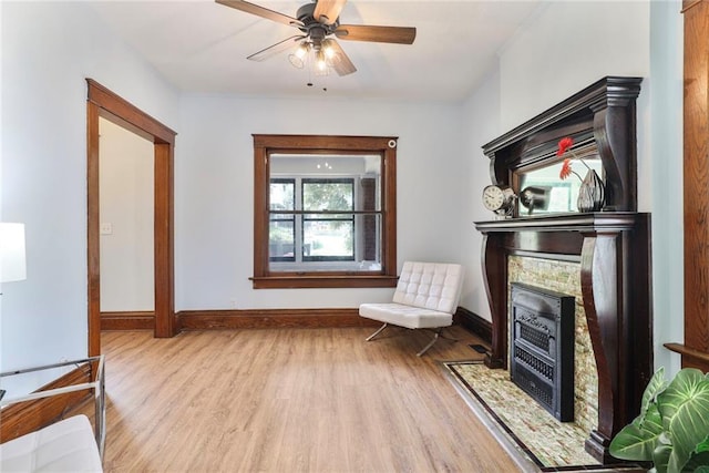 3521 Windsor Ave, Kansas City, MO 64123 - living area with wood finished floors, baseboards, a fireplace with flush hearth, and a ceiling fan