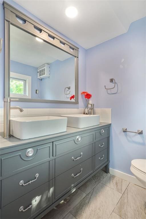 3521 Windsor Ave, Kansas City, MO 64123 - bathroom featuring vanity, toilet, baseboards, and an AC wall unit