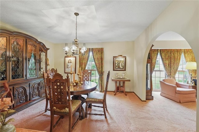 8206 Parkhill Cir, Lenexa, KS 66215 - carpeted dining space with a chandelier, arched walkways, and a textured ceiling