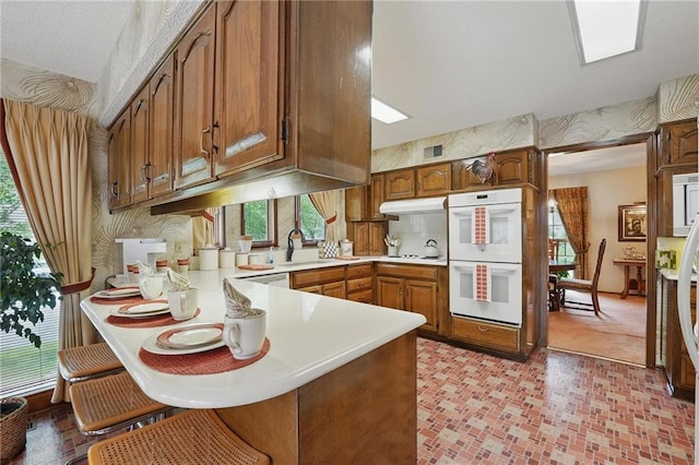 8206 Parkhill Cir, Lenexa, KS 66215 - kitchen with white appliances, under cabinet range hood, a peninsula, light countertops, and healthy amount of natural light