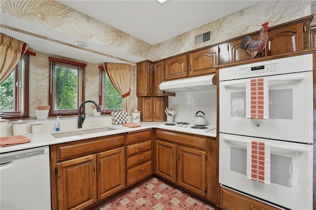 8206 Parkhill Cir, Lenexa, KS 66215 - kitchen with white appliances, under cabinet range hood, light countertops, brown cabinets, and wallpapered walls