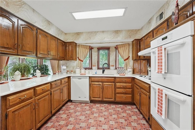 8206 Parkhill Cir, Lenexa, KS 66215 - kitchen with white appliances, light countertops, brown cabinetry, light flooring, and under cabinet range hood