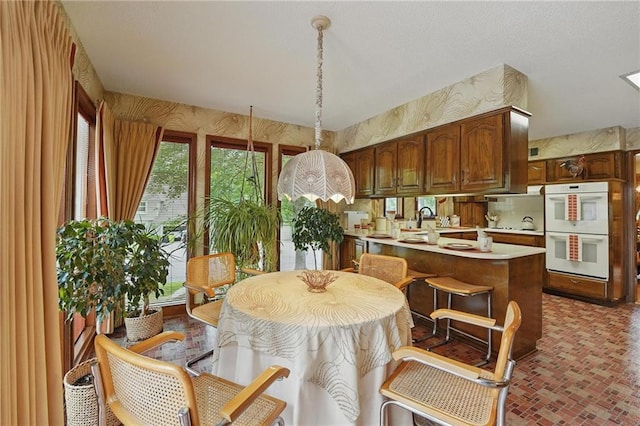 8206 Parkhill Cir, Lenexa, KS 66215 - kitchen with white double oven, light countertops, a peninsula, brick patterned floors, and hanging light fixtures