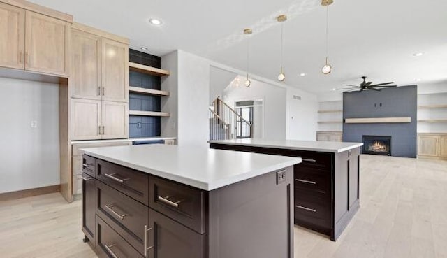 22076 W 99th Ter, Lenexa, KS 66220 - kitchen with a kitchen island, light wood finished floors, ceiling fan, open shelves, and a large fireplace