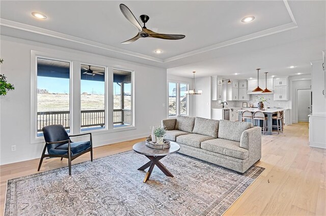 21901 W 99th Ter, Lenexa, KS 66220 - living area featuring a ceiling fan, a tray ceiling, light wood-type flooring, recessed lighting, and ornamental molding