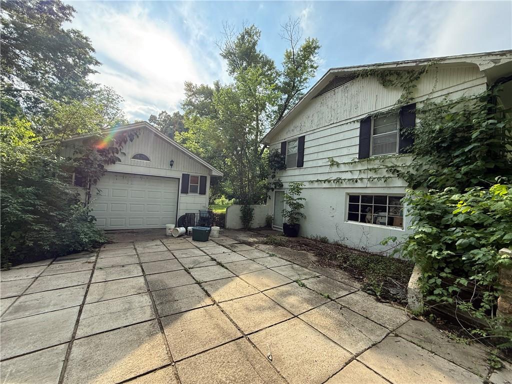 6310 River Rd, Pleasant Valley, MO 64068 - view of patio featuring concrete driveway, an outbuilding, and an attached garage