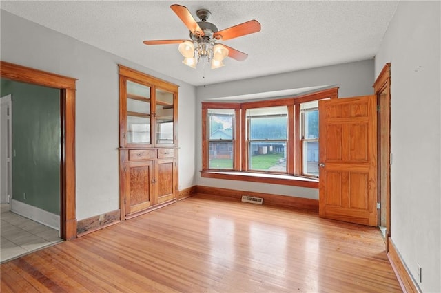 800 Brown Ave, Osawatomie, KS 66064 - empty room featuring light wood finished floors, ceiling fan, healthy amount of natural light, a textured ceiling, and baseboards