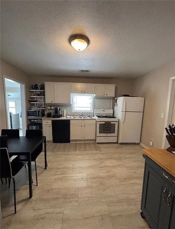 501 W Mcpherson St, Knob Noster, MO 65336 - kitchen with white appliances, a textured ceiling, white cabinets, a sink, and light countertops