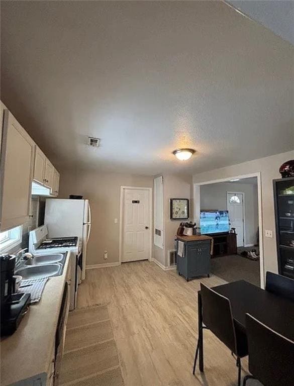501 W Mcpherson St, Knob Noster, MO 65336 - kitchen with light wood-style flooring, white cabinetry, baseboards, a sink, and a textured ceiling