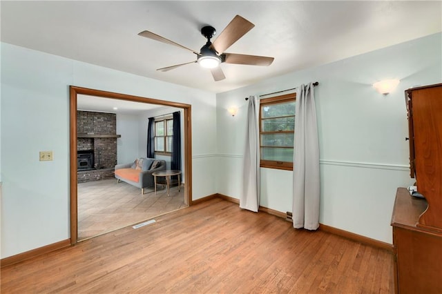 4820 Stearns Ln, Shawnee, KS 66203 - spare room featuring light wood finished floors, plenty of natural light, a ceiling fan, and a fireplace