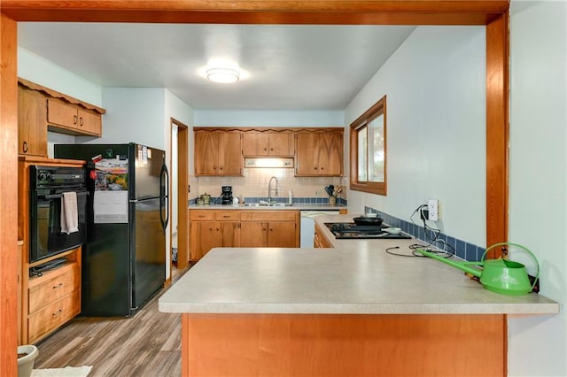 4820 Stearns Ln, Shawnee, KS 66203 - kitchen featuring black appliances, light wood finished floors, light countertops, a peninsula, and decorative backsplash