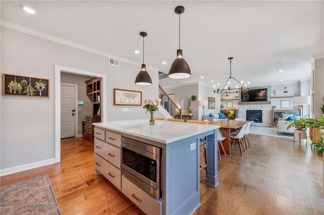 1505 SW Georgetown Dr, Lees Summit, MO 64082 - kitchen featuring stainless steel microwave, crown molding, a fireplace, pendant lighting, and light countertops
