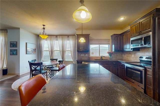 3201 SE 3rd St, Lees Summit, MO 64063 - kitchen with appliances with stainless steel finishes, ornamental molding, decorative backsplash, decorative light fixtures, and dark stone counters