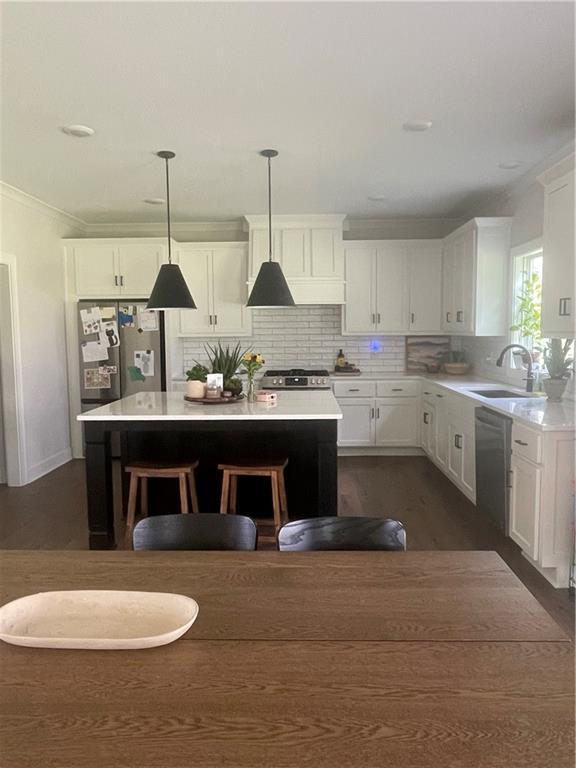 3117 SW Arbor Tree Dr, Lees Summit, MO 64082 - kitchen with stainless steel appliances, a sink, white cabinetry, light countertops, and a kitchen island