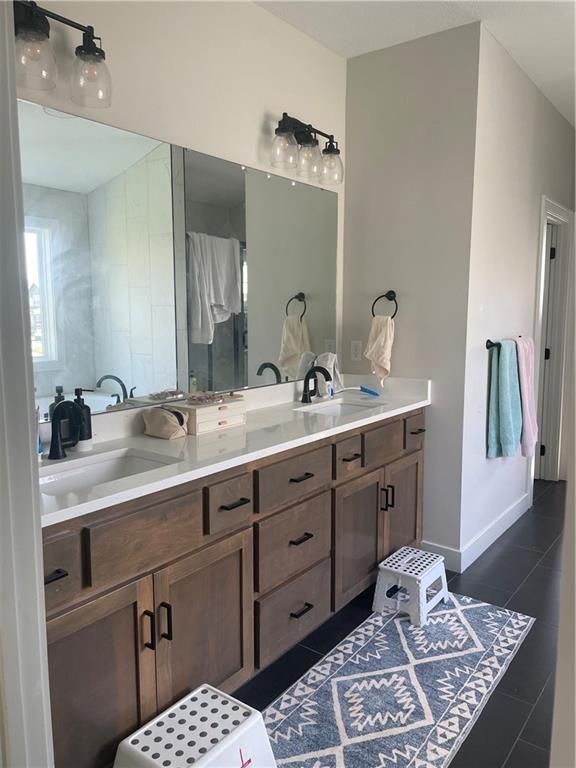 3117 SW Arbor Tree Dr, Lees Summit, MO 64082 - bathroom featuring double vanity, tile patterned floors, baseboards, and a shower stall