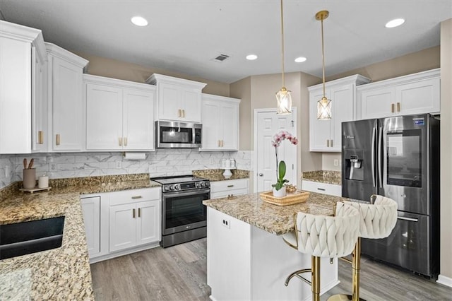 1420 SW Cornwall Rd, Lees Summit, MO 64083 - kitchen with stainless steel appliances, light wood-style floors, white cabinetry, light stone countertops, and recessed lighting
