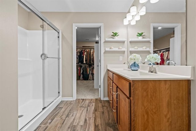 1420 SW Cornwall Rd, Lees Summit, MO 64083 - bathroom with wood finished floors, a spacious closet, a stall shower, and double vanity