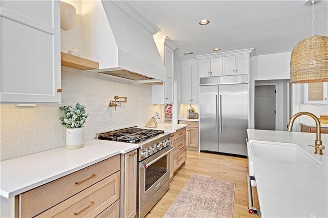 17029 King St, Overland Park, KS 66221 - kitchen with high quality appliances, custom exhaust hood, pendant lighting, light wood-style flooring, and decorative backsplash