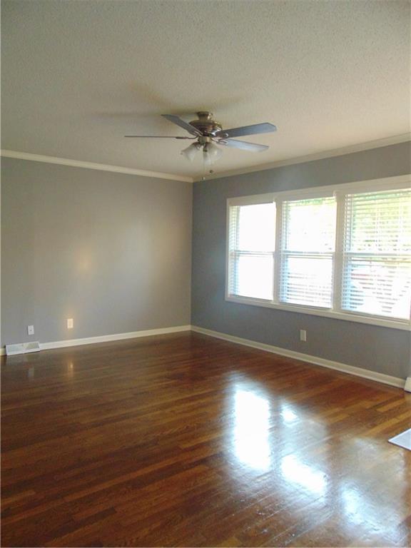 241 E S St, Peculiar, MO 64078 - spare room featuring ceiling fan, dark wood-style floors, crown molding, and a textured ceiling