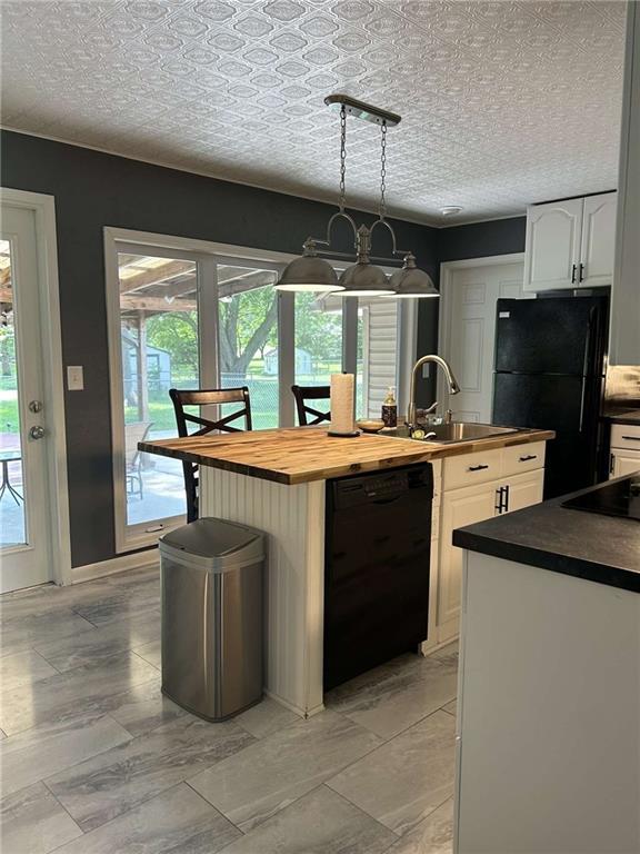 241 E S St, Peculiar, MO 64078 - kitchen with black appliances, butcher block countertops, white cabinetry, a center island with sink, and pendant lighting