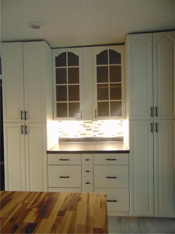 241 E S St, Peculiar, MO 64078 - kitchen with wooden counters, white cabinets, and glass insert cabinets