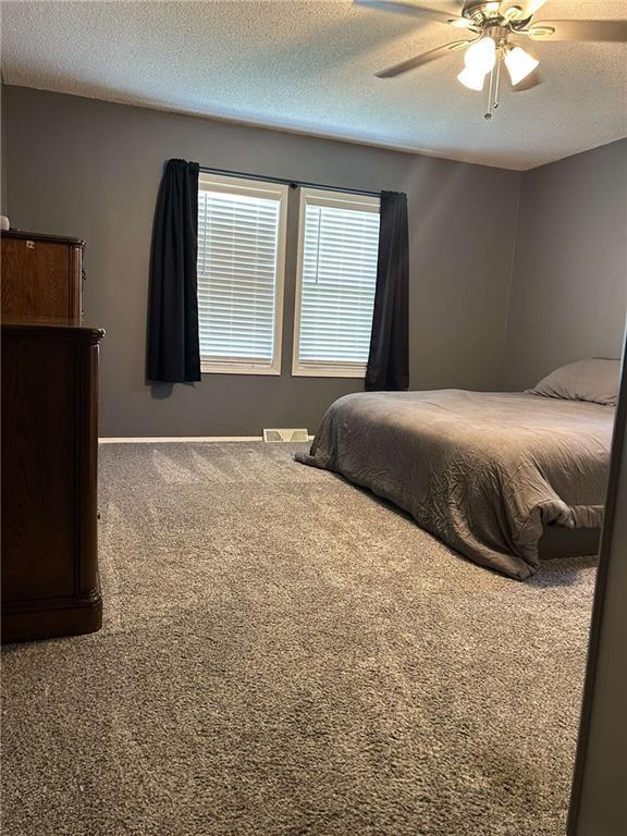 241 E S St, Peculiar, MO 64078 - bedroom with carpet, a textured ceiling, and a ceiling fan