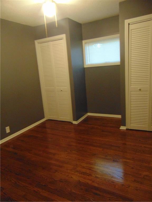 241 E S St, Peculiar, MO 64078 - unfurnished bedroom with a closet, wood finished floors, and a ceiling fan