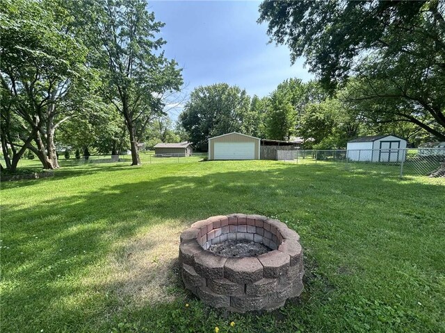 241 E S St, Peculiar, MO 64078 - view of yard featuring a fire pit, an outdoor structure, and a detached garage