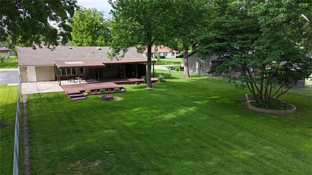 241 E S St, Peculiar, MO 64078 - view of green lawn with an outdoor fire pit, a deck, and a patio