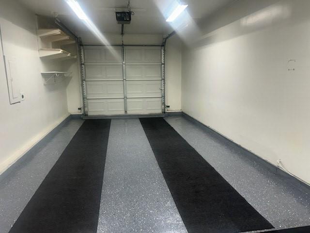 241 E S St, Peculiar, MO 64078 - garage featuring a garage door opener and baseboards