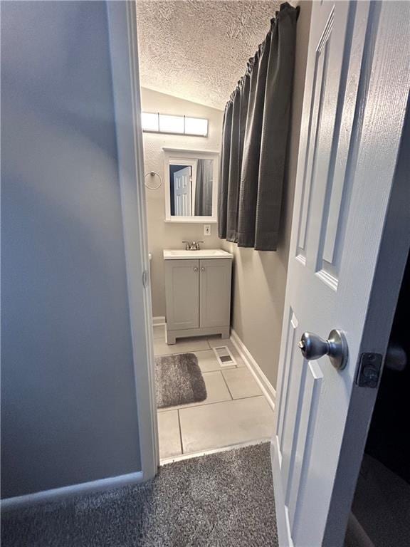409 N Geronimo Dr, Independence, MO 64056 - bathroom featuring lofted ceiling, vanity, tile patterned flooring, and a textured ceiling