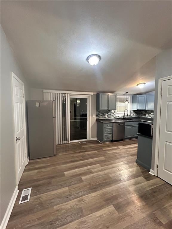 409 N Geronimo Dr, Independence, MO 64056 - kitchen with stainless steel appliances, dark countertops, gray cabinets, dark wood-style floors, and backsplash