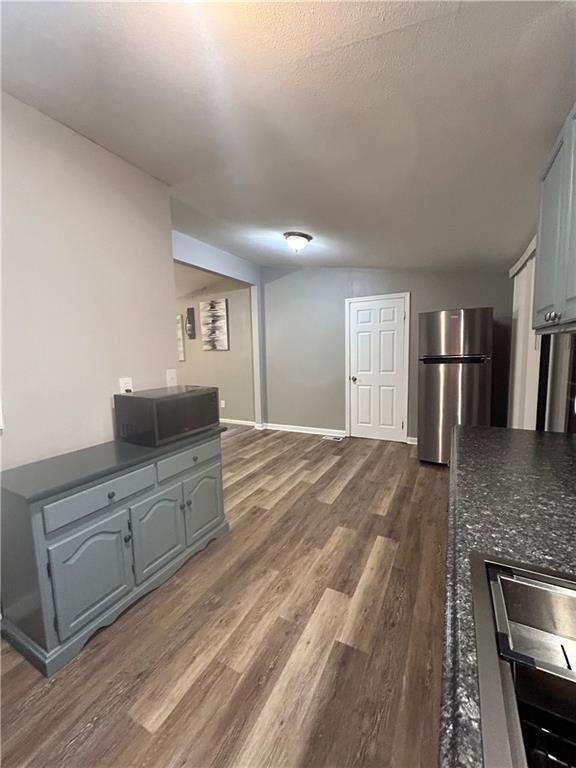 409 N Geronimo Dr, Independence, MO 64056 - kitchen featuring freestanding refrigerator, dark wood-type flooring, dark countertops, and gray cabinets