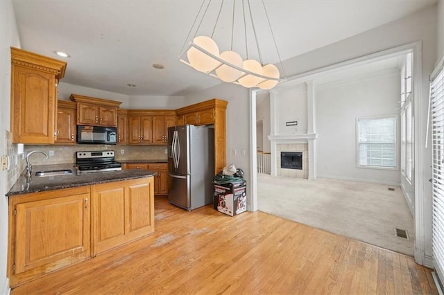 7633 W 148th Ter, Overland Park, KS 66223 - kitchen featuring stainless steel appliances, backsplash, a peninsula, light wood-style floors, and brown cabinetry