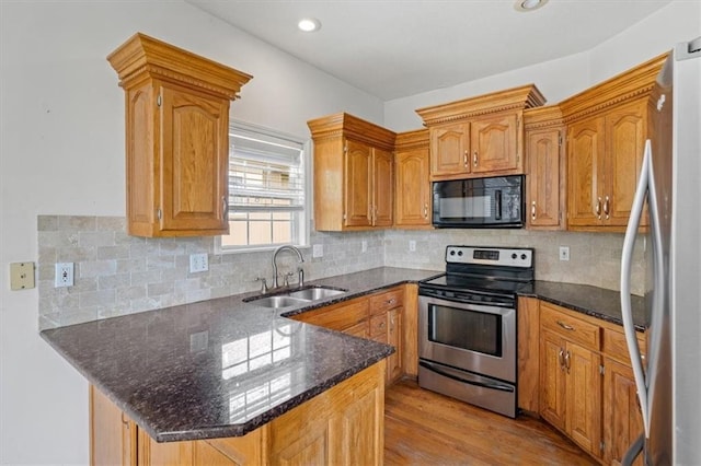 7633 W 148th Ter, Overland Park, KS 66223 - kitchen featuring stainless steel appliances, a peninsula, light wood finished floors, dark stone counters, and decorative backsplash