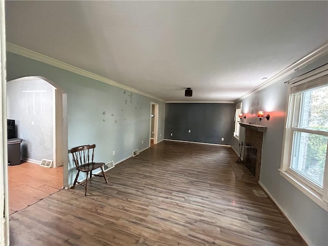 8719 E 57th St, Raytown, MO 64129 - unfurnished living room with a fireplace, arched walkways, wood finished floors, and ornamental molding