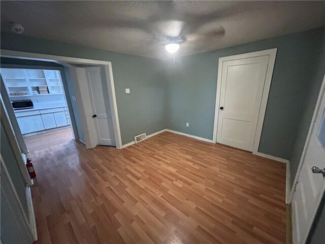 8719 E 57th St, Raytown, MO 64129 - empty room with wood finished floors, a textured ceiling, a smoke detector, and ceiling fan