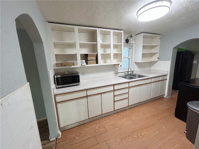 8719 E 57th St, Raytown, MO 64129 - kitchen featuring stainless steel microwave, arched walkways, open shelves, a textured ceiling, and white cabinets