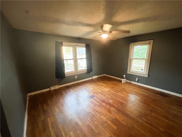 8719 E 57th St, Raytown, MO 64129 - spare room with healthy amount of natural light, a ceiling fan, wood finished floors, and a textured ceiling