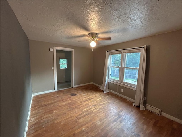 8719 E 57th St, Raytown, MO 64129 - empty room with a textured ceiling, plenty of natural light, wood finished floors, and a ceiling fan