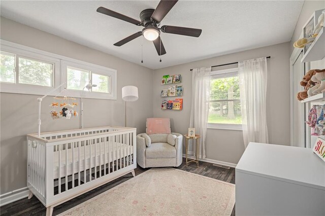 7135 Conser St, Overland Park, KS 66204 - bedroom with multiple windows, dark wood-type flooring, a crib, and ceiling fan