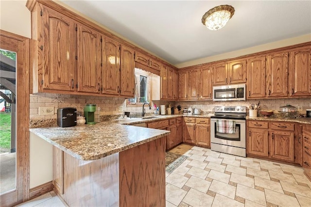 3917 SW Windjammer Ct, Lees Summit, MO 64082 - kitchen with appliances with stainless steel finishes, a peninsula, tasteful backsplash, a sink, and brown cabinetry