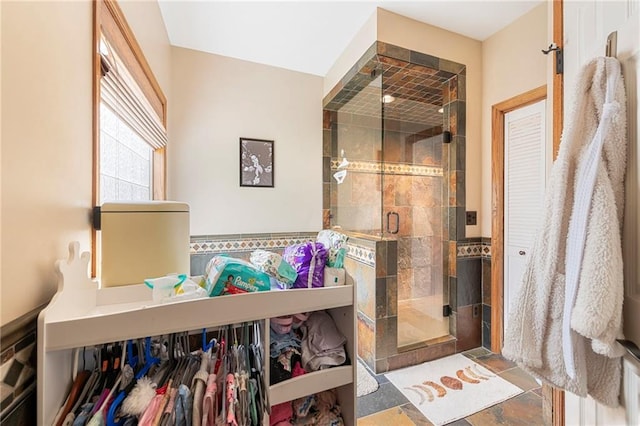 3917 SW Windjammer Ct, Lees Summit, MO 64082 - bathroom featuring a stall shower, tile walls, stone finish floors, and a wainscoted wall
