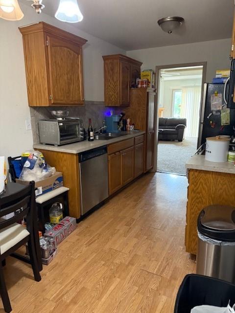 1235 Ashley Ln, Grain Valley, MO 64029 - kitchen featuring appliances with stainless steel finishes, light wood-style flooring, light countertops, and brown cabinetry