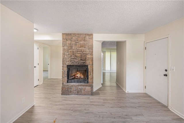 2701 NW 5th St, Blue Springs, MO 64014 - unfurnished living room with a textured ceiling, a stone fireplace, and wood finished floors