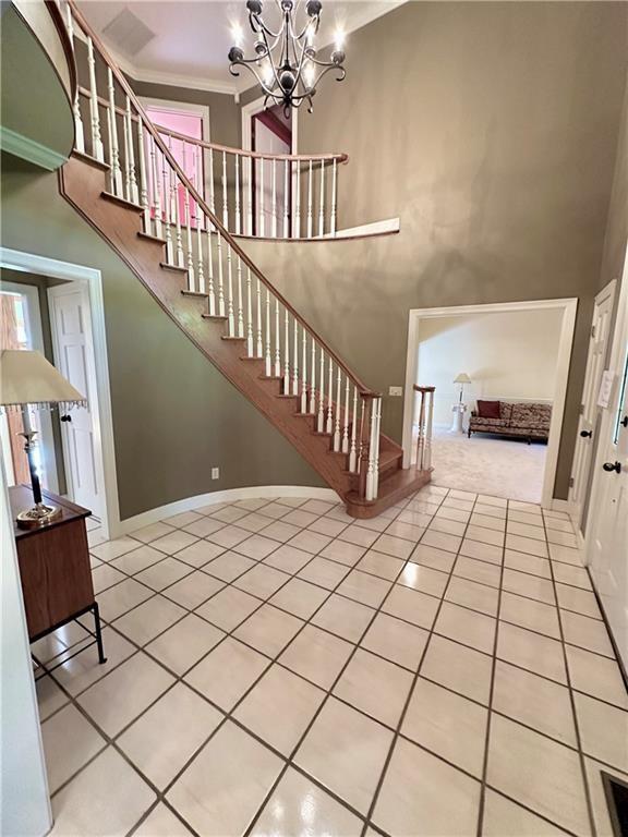925 S Walnut St, Maryville, MO 64468 - stairway with a high ceiling, tile patterned flooring, a chandelier, baseboards, and crown molding